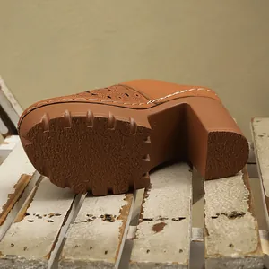 Detail view of brown chunky heel clogs with floral laser-cut patterns and textured sole