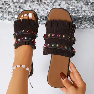 Detailed view of brown fringe slides with colorful studs and white pearl anklet.