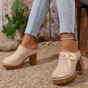 Detail of beige patent leather platform mules with chunky heels and gold buckles