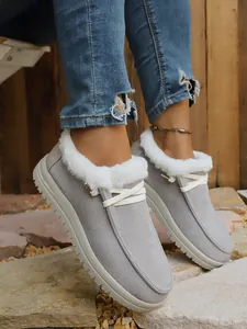 Close-up of women's grey warm fur-lined snow boots with white lace-up and thick sole
