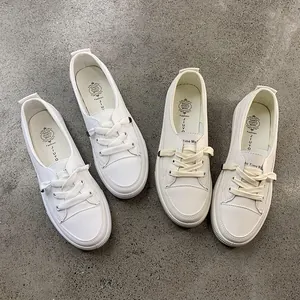 Four white minimalist women's board sneakers displayed on a gray concrete background