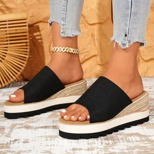 Gros plan de mules compensées en toile noire avec plateforme en jute tressée