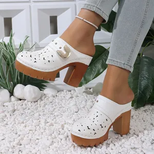 Detail view of white laser-cut mule shoes with chunky wooden platform and gold buckle.