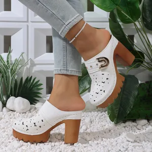 Macro view of white hollow-out platform mules featuring metal buckle and chunky heel