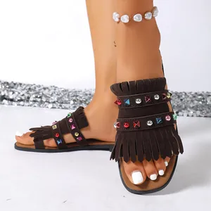 Close-up detail of women's brown suede flat sandals featuring colorful rhinestones and tassels