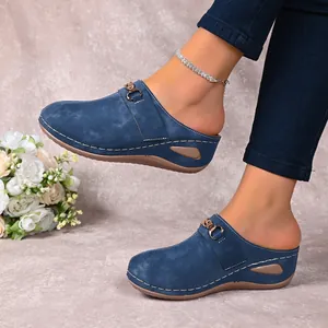 Close-up of stylish blue wedge mules with gold buckle detail on a model's feet