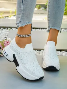 Nahaufnahme weißer Slip-on-Sneaker mit glitzernden Strasssteinen und dicken Luftpolstersohlen
