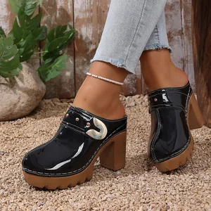 Detailed view of black patent leather platform clogs with chunky heels and rivets