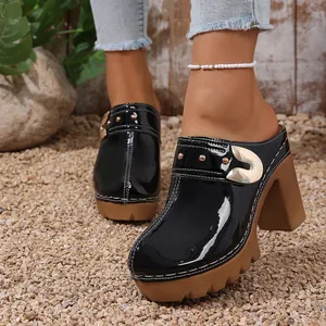 Close-up of elegant black patent leather platform mules featuring rivets and buckle