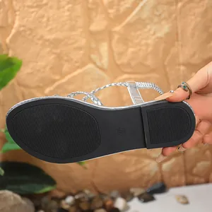 Close-up detail of the durable anti-slip rubber sole on silver braided flat thong sandals