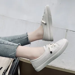 Detailed view of minimalist beige women's casual plimsolls worn with denim jeans.