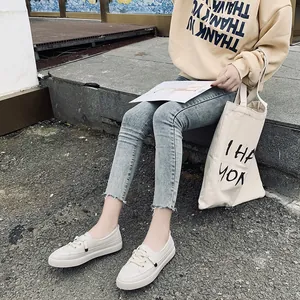 Modern white casual board shoes for women styled with a yellow hoodie and denim jeans.