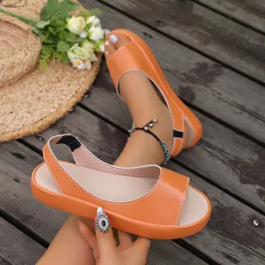 Detailopname van oranje platte sandalen met open teen en comfortabele elastische band