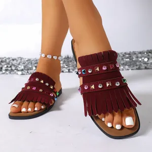 Detailed view of burgundy suede flat sandals with stylish fringe and colorful studs