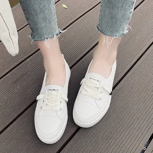 Detailed macro view of stylish white casual leather sneakers on a wooden deck with blue jeans