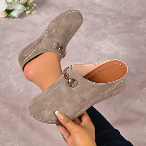 Detailed view of khaki platform mules featuring a gold chain buckle and stitching.