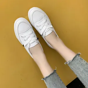 Top-down view of stylish white casual board shoes with laces worn with frayed denim jeans.