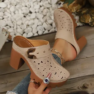 Close-up view of stylish closed-toe chunky heel mules featuring floral laser-cut patterns.