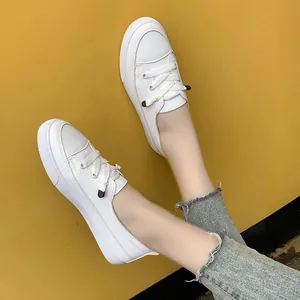Detail of minimalist white leather low-top sneakers on model with yellow background.