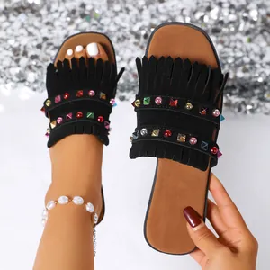 Detail view of stylish black flat sandals featuring trendy fringe and colorful rhinestones.