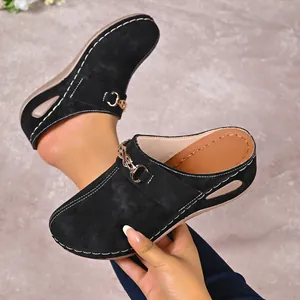 Detail of black wedge mules for women featuring gold chain and white stitching