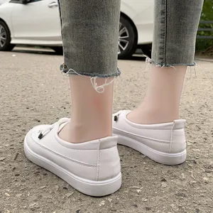 Detail view of minimalist white leather women's sneakers with frayed denim jeans