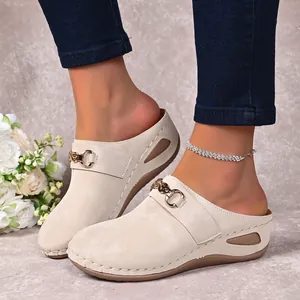 Detailed view of women's beige wedge closed-toe mules featuring elegant metal buckle
