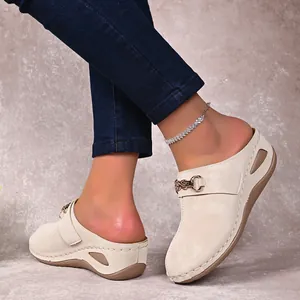 Close-up view of beige women's wedge mules featuring a stylish gold chain ornament
