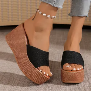 Gros plan de sandales compensées noires avec texture paille et bride scintillante