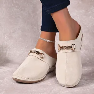 Close-up of cream women's wedge mules featuring stylish gold chain buckle details