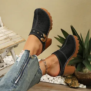 Detailed view of women's black laser-cut closed-toe clogs featuring thick brown heels
