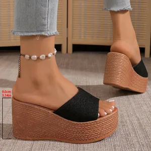 Détail rapproché de sandales compensées noires avec talon plateforme tressé de 9 cm
