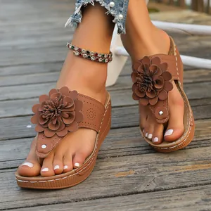 Close-up of brown wedge thong sandals with decorative flower on wooden deck