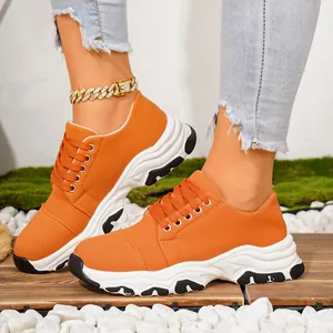 Detail view of vibrant orange chunky sole sneakers worn with denim and accessories