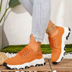 Detailed side view of orange thick-sole women's running shoes on a model