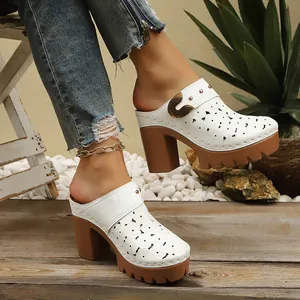 White laser-cut platform mules with chunky brown heels on model