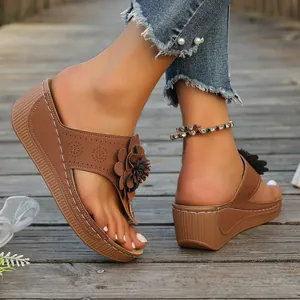 Detailed view of brown platform flip-flops with flower decoration on wooden path
