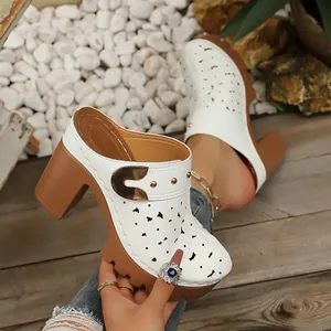 Close-up detail of white floral laser-cut platform mules with stylish gold metal buckle