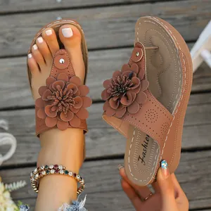 Detail view of brown wedge flip-flop sandals featuring a stylish large flower decoration