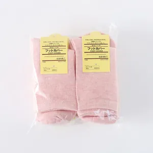 Macro detail of two pairs of pink ribbed cotton foot cover socks in transparent packaging
