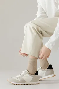 Détail de chaussettes en coton kaki pour hommes avec baskets rétro et pantalon beige.