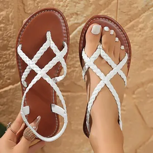 Detail of white braided straps on brown flat thong sandals with elastic back
