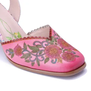Detalle de cerca del exquisito bordado floral en las sandalias de cuero rosa de estilo vintage.