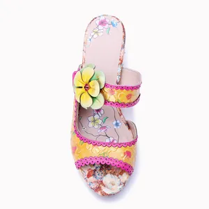 Detail eines handbemalten Retro-Blumenmusters und einer 3D-Blume auf einer Ledersandale.