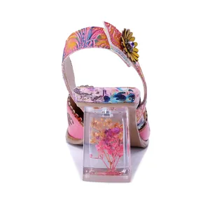 Vista de detalle de sandalia rosa vintage con tacón transparente único que contiene flores secas.