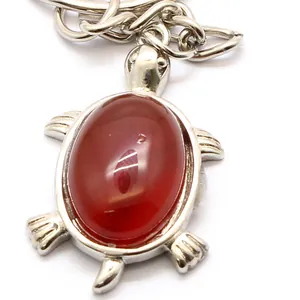 Elegant turtle-shaped keychain pendant with a vibrant red crystal gem on white background