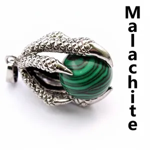 Detailed macro shot of a vintage silver dragon claw pendant with a green malachite bead