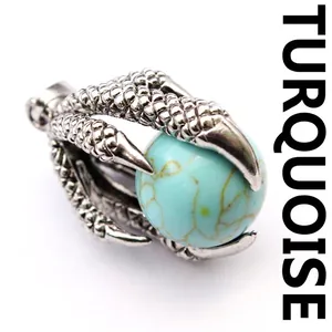 Macro view of a medieval style silver dragon claw pendant holding a round turquoise stone bead