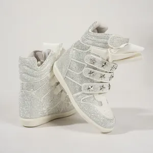 Detailed view of white rhinestone sneakers with star studs and wedge heels