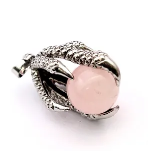Detailed macro view of a vintage silver dragon claw pendant holding a pink bead.